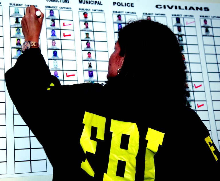 female fbi agent check marking suspects captured on white board